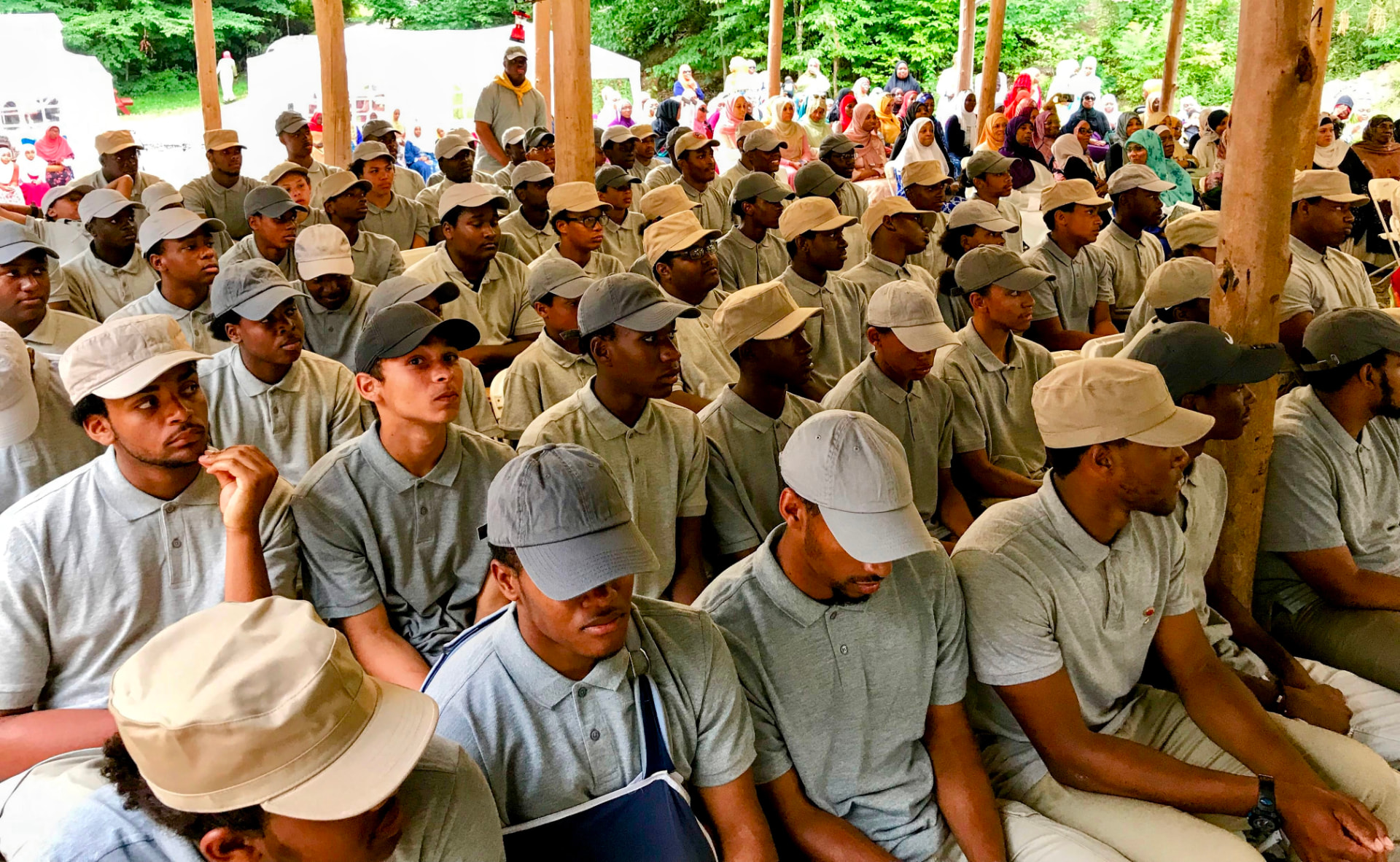 Rows of Muslim Scouts in uniform seated together at a camp assembly